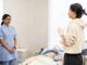 Two nurses in a room with a model patient on bed