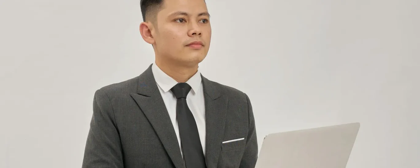 A business person with a laptop in a suit and tie