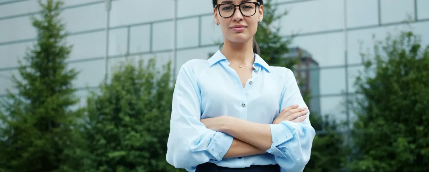 A businesswoman in a blue shirt outside a glass building
