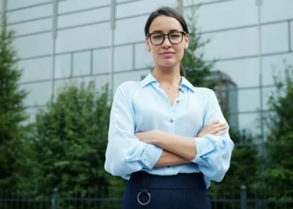 A businesswoman in a blue shirt outside a glass building