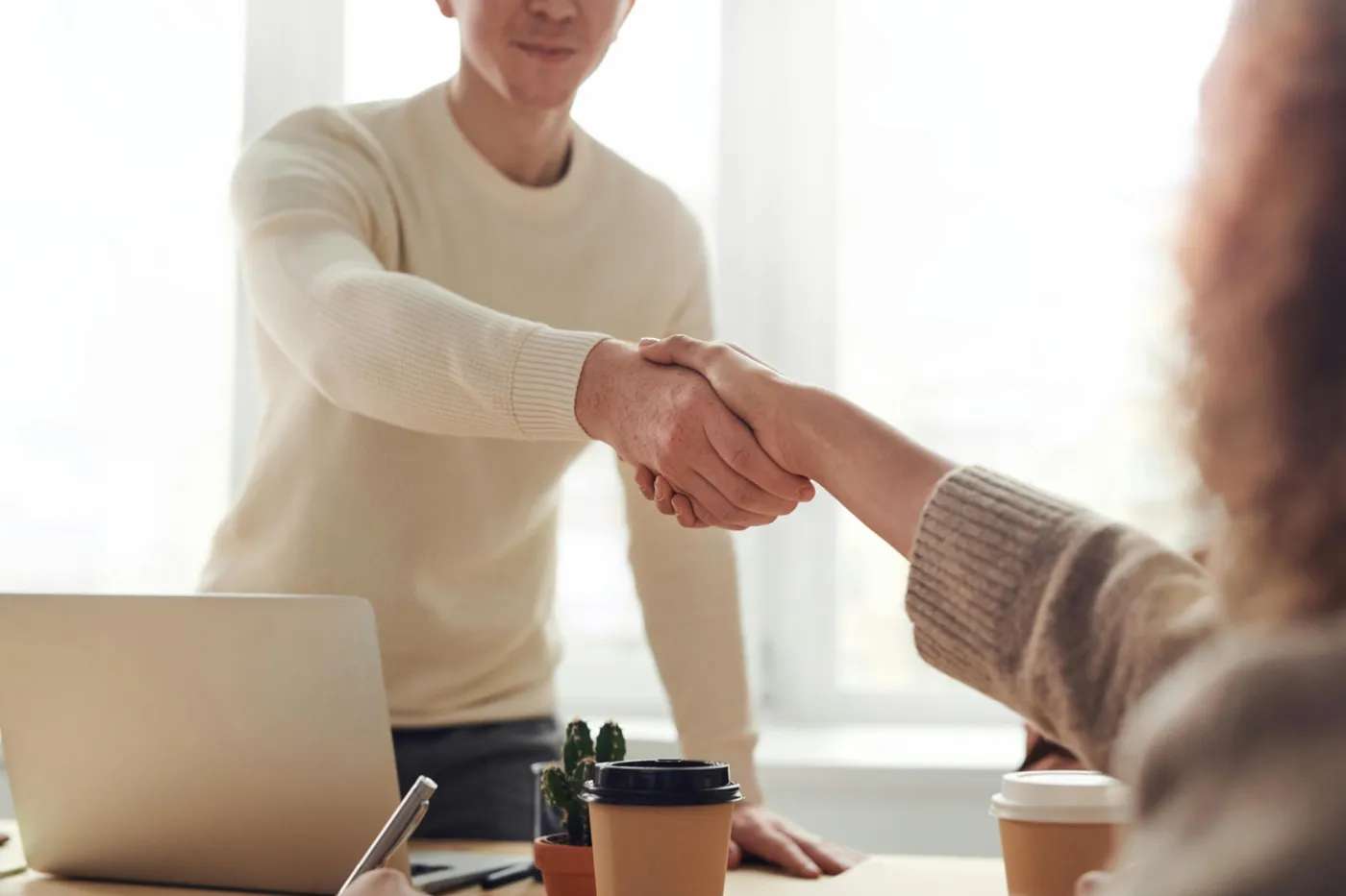 Two people shaking hands in a service supplier meeting